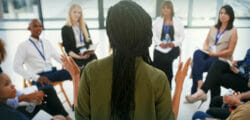 Group of employees circle around leader to discuss